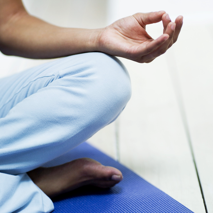 Person meditating on blue mat.
